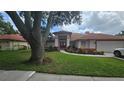 Beautifully landscaped home with a well-manicured lawn, red trim, and covered entry at 16502 Windsor Park Dr, Lutz, FL 33549