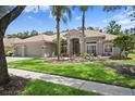 Charming home featuring lush landscaping, mature palm trees, and a tile roof at 17818 Arbor Greene Dr, Tampa, FL 33647