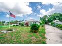 Quaint single-Gathering house with a metal roof, green lawn, landscaping, and an American flag waving proudly at 2060 Saffold Park Dr, Ruskin, FL 33570