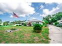 Quaint single-Gathering house with a metal roof, green lawn, landscaping, and an American flag in the yard at 2060 Saffold Park Dr, Ruskin, FL 33570