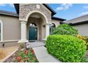Inviting home entrance with stone archway, and lush landscaping at 3411 Knoxville Pl, Plant City, FL 33566