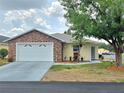 Charming single-story home showcasing a brick facade, manicured landscaping, and a two-car garage at 5755 Yorkshire Dr, Zephyrhills, FL 33542