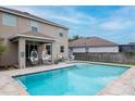 Backyard with a beautiful in-ground pool and covered patio area with stylish hanging chairs and outdoor seating at 5916 Tulip Flower Dr, Riverview, FL 33578