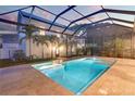Backyard pool and spa are enclosed with screen, surrounded by travertine tile and lush landscaping at 608 Grove N St, St Petersburg, FL 33701