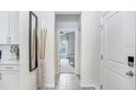 Bright, modern hallway with tile floors, a decorative mirror, and an open doorway to another room at 11739 Blackbrook Ct, Seffner, FL 33584