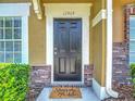 Stylish black front door with brick accents and decorative 'Stay Awhile' welcome mat at 12464 Berkeley Square Dr, Tampa, FL 33626