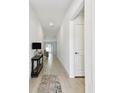 Bright and airy hallway with neutral tile flooring and a console table with decor, leading to the living areas at 13235 Palmerston Rd, Riverview, FL 33579
