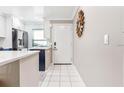 Bright entryway with white tile flooring, complemented by kitchen featuring stainless steel appliances in background at 1371 Mission Hills Blvd, Clearwater, FL 33759
