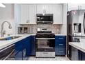 Charming kitchen boasting white cabinets, stainless steel appliances, and stylish blue lower cabinets at 1371 Mission Hills Blvd, Clearwater, FL 33759