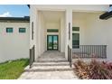 Welcoming entrance with tiled steps, black metal railings, and modern lighting fixtures at 15218 Appleton Blvd, Port Charlotte, FL 33981