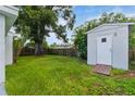 Expansive backyard featuring green lawn space, a storage shed, and a mature tree providing shade at 4318 Mesa Dr, New Port Richey, FL 34653