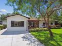 Inviting single-story home featuring a well-manicured lawn, lovely garden beds, and an asphalt driveway at 4522 S Hale Ave, Tampa, FL 33611