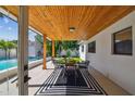Inviting covered patio with wood ceiling, black and white rug, and view of the sparkling pool at 4522 S Hale Ave, Tampa, FL 33611