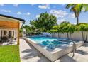 Lush backyard oasis featuring a pristine pool, spa, patio with dining area, and mature tropical landscaping at 4522 S Hale Ave, Tampa, FL 33611
