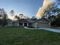 Charming single-Gathering home with a two-car garage, lush green lawn, and mature trees at 6153 La Pine Rd, Brooksville, FL 34602