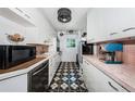 Efficient kitchen with white cabinets, black and white tile floors, and pink tile backsplash at 841 4Th N Ave # 21, St Petersburg, FL 33701