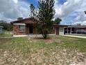 Cozy single-story house featuring brick accents and a covered entrance, surrounded by a green lawn and trees at 9218 N 52Nd St, Tampa, FL 33617