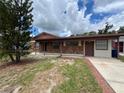 Single-story brick house featuring a welcoming front porch and a mature tree in the yard at 9218 N 52Nd St, Tampa, FL 33617