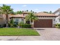Inviting one-story house featuring a tile roof, well-kept lawn, mature landscaping, and a two-car garage at 10880 Cory Lake Dr, Tampa, FL 33647