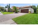 A home with a dark-stained, two car garage and a brick-paved driveway at 10880 Cory Lake Dr, Tampa, FL 33647