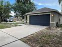 Street view of a single-story home with a two-car garage, large driveway and landscaped yard at 15421 Shoal Haven Pl, Ruskin, FL 33573