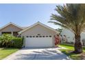 Attractive house featuring a manicured yard, swaying palm tree, and a wide driveway to the two-car garage at 1729 Arabian Ln, Palm Harbor, FL 34685