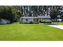 Single-story home featuring a lush green lawn and an attached carport and additional storage shed at 19209 Crooked Ln, Lutz, FL 33548