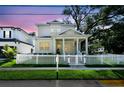Inviting two-story home with a charming front porch, white picket fence, and picturesque curb appeal at dusk at 238 7Th S Ave, Safety Harbor, FL 34695