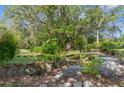 Lush backyard featuring a serene pond with aquatic plants, surrounded by stone edging and paving stones at 3373 Olson Rd, Spring Hill, FL 34607