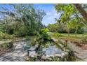 Picturesque backyard with a tranquil pond, rock border, lush plants, and a glimpse of the American flag at 3373 Olson Rd, Spring Hill, FL 34607