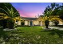 Charming single-story home with lush lawn, palm trees, and inviting curb appeal at dusk at 3628 Dellefield St, New Port Richey, FL 34655