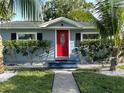 Cozy single-story home featuring a bright red front door, tidy landscaping, and tropical palm trees at 3980 55Th N Ave, St Petersburg, FL 33714