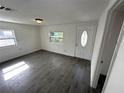 Bright living room featuring gray wood-look tile floors, a modern ceiling light, and a white front door with glass at 3980 55Th N Ave, St Petersburg, FL 33714