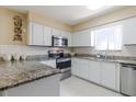 A well-lit kitchen featuring white cabinets, stainless steel appliances, granite countertops, and white tiled backsplash at 4030 Cortez Dr # C, Tampa, FL 33614