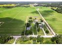 Expansive aerial view of a property with mature trees and bordered by lush green agricultural fields at 4030 Moores Lake Rd, Dover, FL 33527