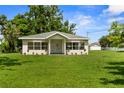 Daytime view of a charming single-story home with a well-manicured lawn and a detached garage at 4030 Moores Lake Rd, Dover, FL 33527