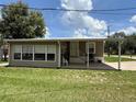 Inviting mobile home featuring a covered porch, verdant lawn, and clear, sunny skies at 5105 Wood St, Zephyrhills, FL 33542