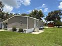 Cozy mobile home boasts a covered porch, landscaped yard with vibrant flowers, and convenient shed at 5105 Wood St, Zephyrhills, FL 33542