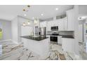 Modern kitchen with white cabinetry, stainless steel appliances, black countertops and marble floors at 5317 Lydia Ct, Spring Hill, FL 34608