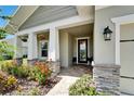 Welcoming front porch with stone accents, decorative plants, and stylish outdoor lighting at 7116 Estero Ct, Apollo Beach, FL 33572