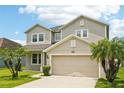 Inviting two-story home boasting a lush lawn, two palm trees, and a two-car garage at 7509 Tangle Bend Dr, Gibsonton, FL 33534