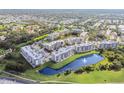 Aerial view of modern condos surrounded by lush greenery, a beautiful pond, and community amenities at 960 Starkey Rd # 7503, Largo, FL 33771