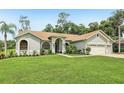 Well-maintained one-story home featuring a well-manicured lawn, an arched entryway, and a three-car garage with a gray exterior at 10113 Bell Creek Dr, Riverview, FL 33569