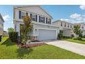 Two-story home featuring blue shutters, a two-car garage, and landscaping at 10580 Gliding Eagle Way, Land O Lakes, FL 34638