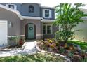 The inviting front entrance features a turquoise door, detailed landscaping, and fresh green lawn at 10605 Marsanne Pl, Riverview, FL 33578