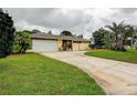 Charming one-story home with a well-manicured lawn, a beautiful curved driveway, and mature palm trees at 1117 S Florida Ave, Tarpon Springs, FL 34689