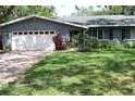 Charming single-story home with a brick driveway, manicured lawn, and attached two-car garage at 12794 Palm Dr, Largo, FL 33774