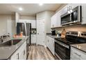 Modern kitchen features white cabinets, stainless steel appliances, gray counter tops, and plank flooring at 14819 Summer Branch Dr Dr, Lithia, FL 33547