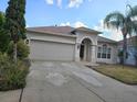 This home has an attached 2-car garage and an arched entryway, enhanced by mature landscaping at 18423 Meadow Blossom Ln, Tampa, FL 33647