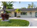 Charming home exterior showcasing a manicured lawn, tropical landscaping, and modern lighting fixtures at 243 45Th Ne Ave, St Petersburg, FL 33703